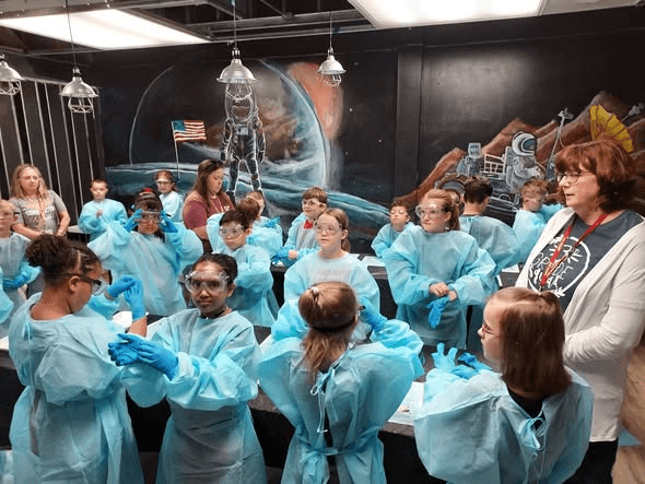 A group of young scientists wearing protective gowns and goggles during a HOSC workshop